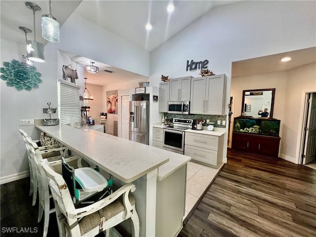 kitchen with tasteful backsplash, light wood-style flooring, a breakfast bar, a peninsula, and stainless steel appliances