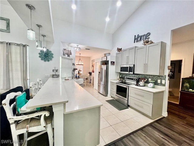 kitchen with stainless steel appliances, a breakfast bar, light countertops, and a peninsula