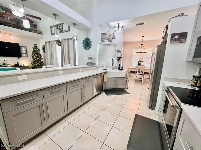 kitchen featuring light tile patterned floors, gray cabinetry, a sink, light countertops, and appliances with stainless steel finishes