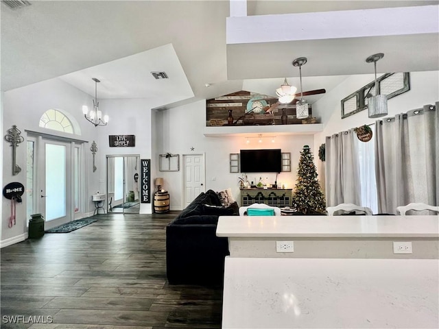 living area with baseboards, visible vents, dark wood-type flooring, high vaulted ceiling, and a notable chandelier