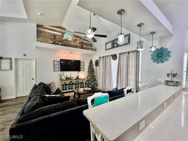 living room featuring ceiling fan, visible vents, high vaulted ceiling, and wood finished floors