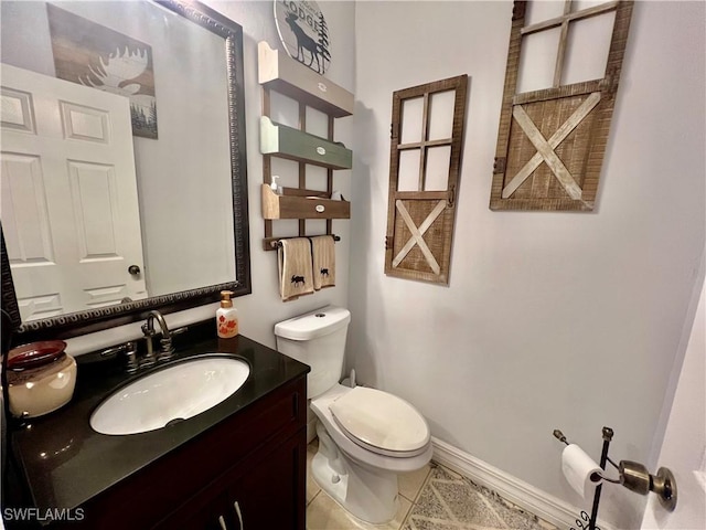 half bath featuring vanity, tile patterned flooring, toilet, and baseboards