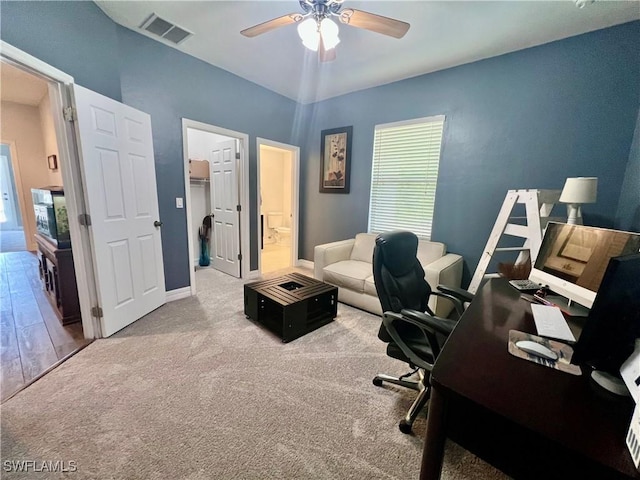 carpeted office space with ceiling fan, visible vents, and baseboards