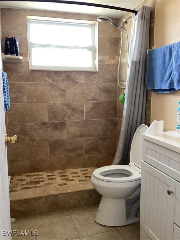 full bath with tile patterned floors, a shower stall, toilet, and a healthy amount of sunlight