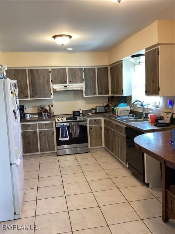 kitchen with dishwasher, dark countertops, freestanding refrigerator, under cabinet range hood, and stainless steel range with electric stovetop