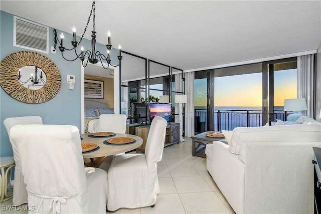 tiled dining room featuring a water view, visible vents, and a textured ceiling