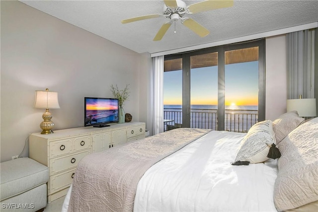 bedroom with access to exterior, ceiling fan, and a textured ceiling