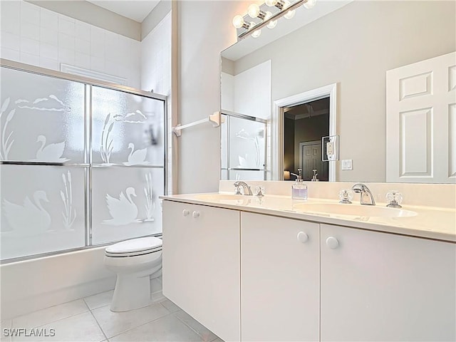 bathroom featuring tile patterned flooring, toilet, bath / shower combo with glass door, and a sink