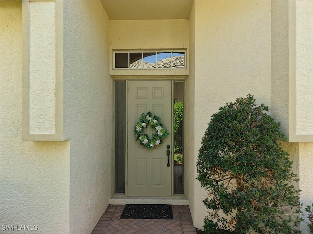 doorway to property featuring stucco siding