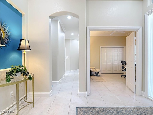 hallway with light tile patterned floors, recessed lighting, arched walkways, and baseboards