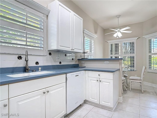 kitchen featuring a sink, a peninsula, white cabinets, and white dishwasher