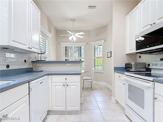 kitchen with visible vents, backsplash, white appliances, and white cabinets