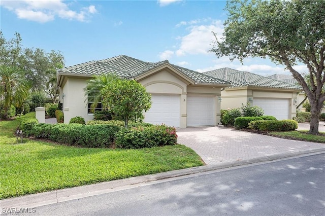 view of front of property with stucco siding, an attached garage, a tile roof, and decorative driveway