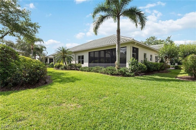 back of house with a sunroom, a lawn, and a tile roof