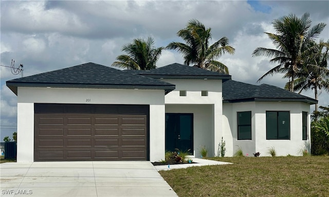 view of front of property featuring a garage, stucco siding, a shingled roof, and a front yard