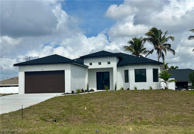 prairie-style home with roof with shingles, stucco siding, concrete driveway, an attached garage, and a front lawn