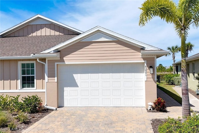 view of front facade featuring a shingled roof, decorative driveway, an attached garage, and board and batten siding