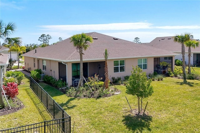 rear view of house with a yard, fence, a shingled roof, and stucco siding