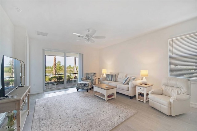 living area with baseboards, light wood-style flooring, visible vents, and a ceiling fan