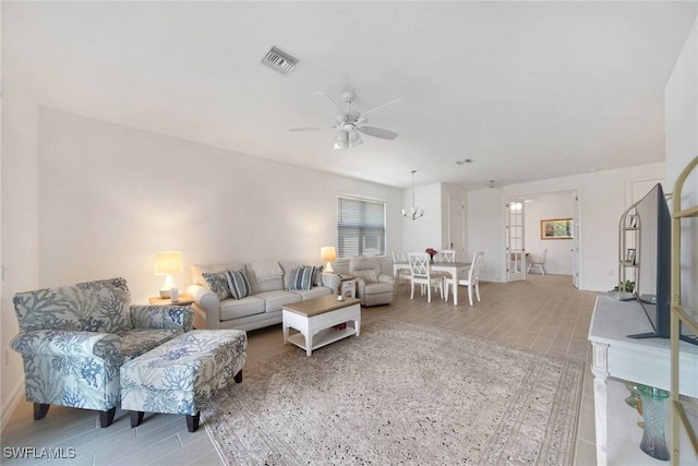 living room featuring a ceiling fan, baseboards, visible vents, and light wood finished floors