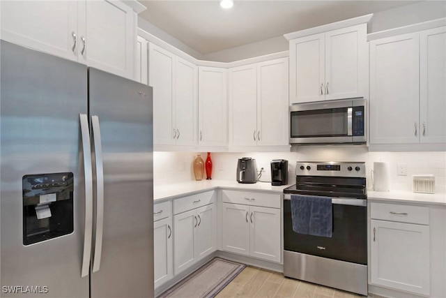 kitchen with white cabinetry, light countertops, appliances with stainless steel finishes, light wood-type flooring, and decorative backsplash