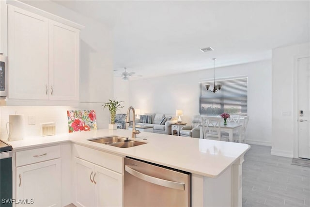 kitchen featuring open floor plan, a peninsula, light countertops, stainless steel dishwasher, and a sink