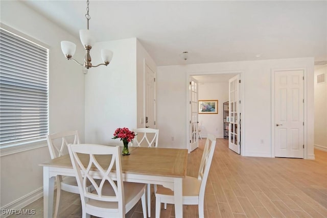 dining space with a chandelier, light wood-type flooring, visible vents, and baseboards