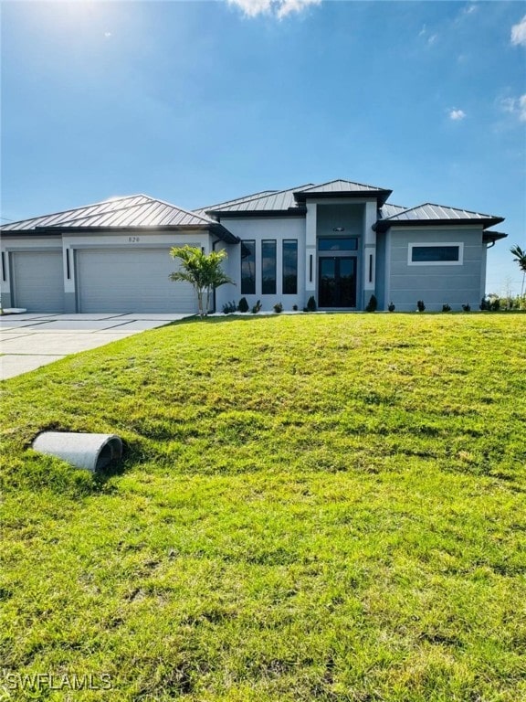 prairie-style home featuring driveway, metal roof, an attached garage, a standing seam roof, and a front yard