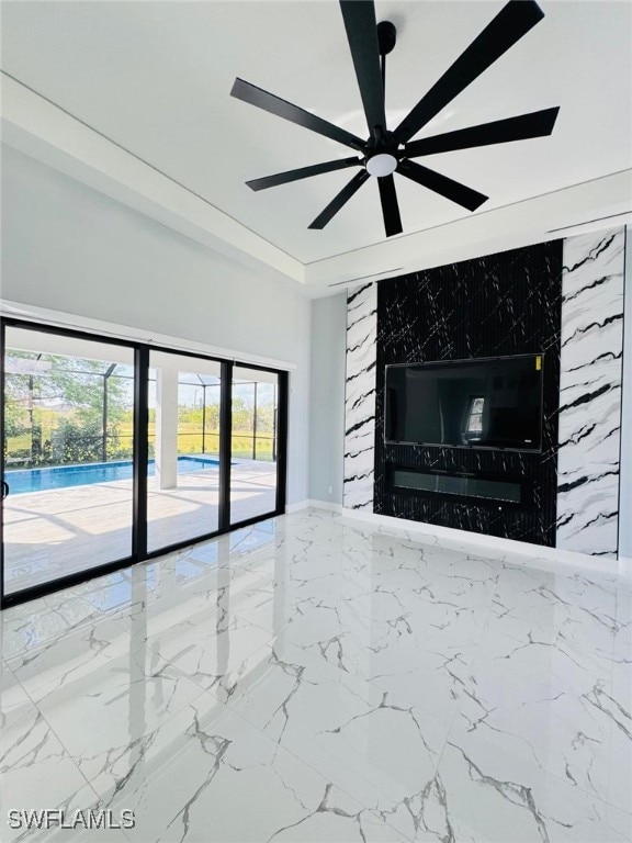 unfurnished living room with a ceiling fan, a raised ceiling, marble finish floor, and a premium fireplace