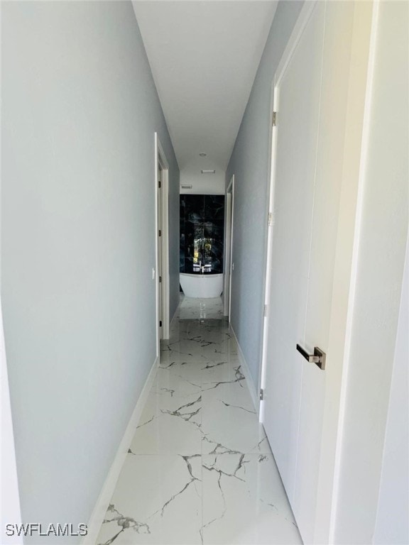 hallway with marble finish floor and baseboards