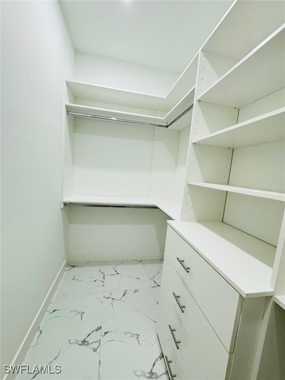 walk in closet featuring marble finish floor