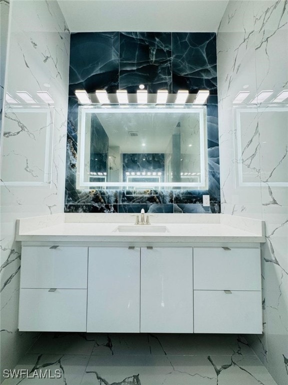 bathroom featuring marble finish floor, stone wall, and vanity