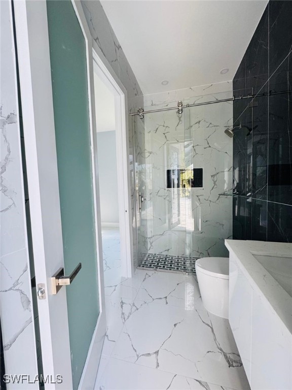 bathroom featuring a marble finish shower, marble finish floor, and toilet