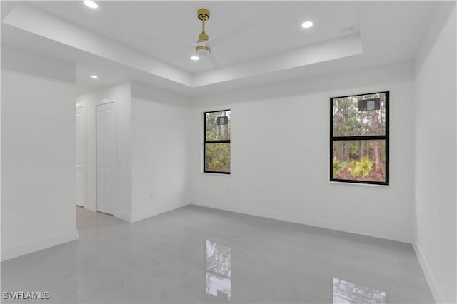 empty room featuring baseboards, a raised ceiling, and recessed lighting