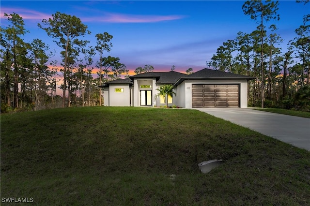 view of front of house with a garage, concrete driveway, and a front lawn