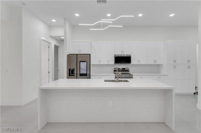 kitchen with visible vents, white cabinets, a kitchen island with sink, stainless steel appliances, and a sink