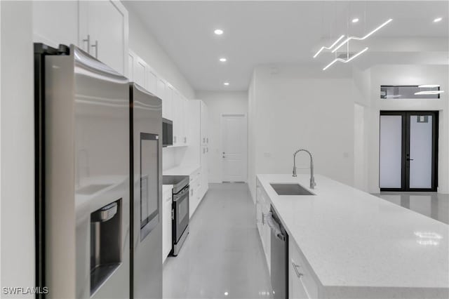 kitchen with recessed lighting, appliances with stainless steel finishes, a kitchen island with sink, white cabinetry, and a sink