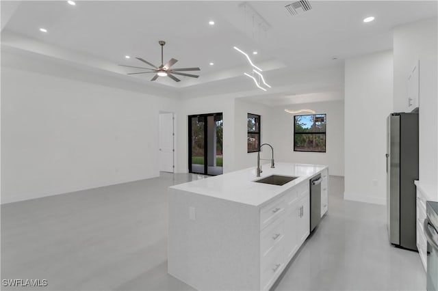 kitchen featuring visible vents, an island with sink, a tray ceiling, stainless steel appliances, and a sink