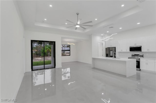 kitchen featuring white cabinets, a tray ceiling, stainless steel appliances, light countertops, and a sink