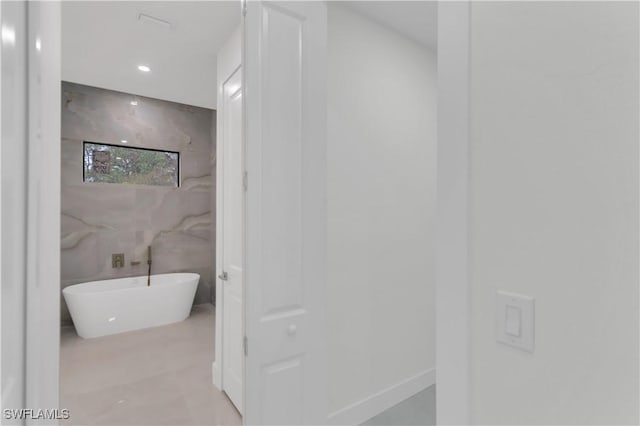 bathroom featuring a freestanding bath, tile walls, and recessed lighting