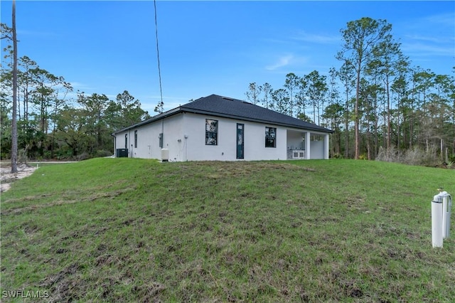 rear view of property featuring a yard and stucco siding