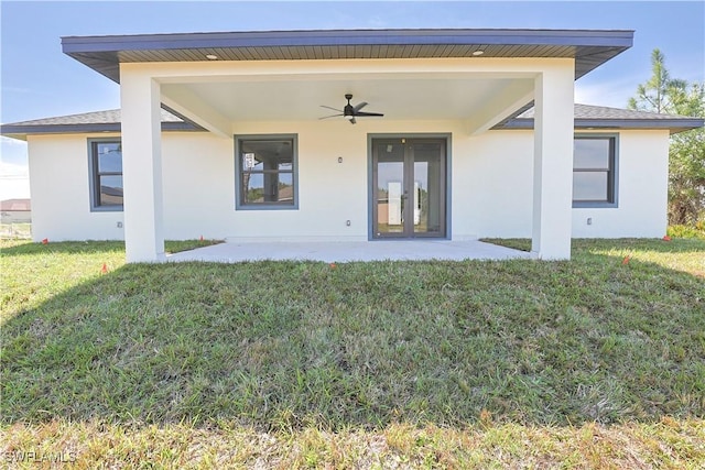 rear view of property featuring a yard, a patio, a ceiling fan, and stucco siding