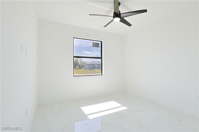 empty room with marble finish floor, baseboards, and a ceiling fan