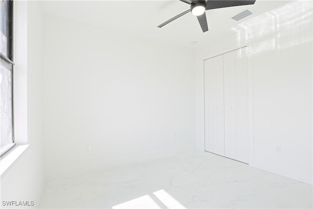 empty room with a ceiling fan, marble finish floor, and visible vents