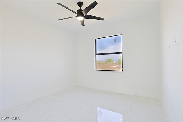 empty room with ceiling fan, marble finish floor, and baseboards