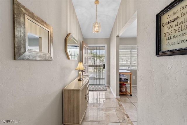 interior space featuring vaulted ceiling, a textured wall, and baseboards