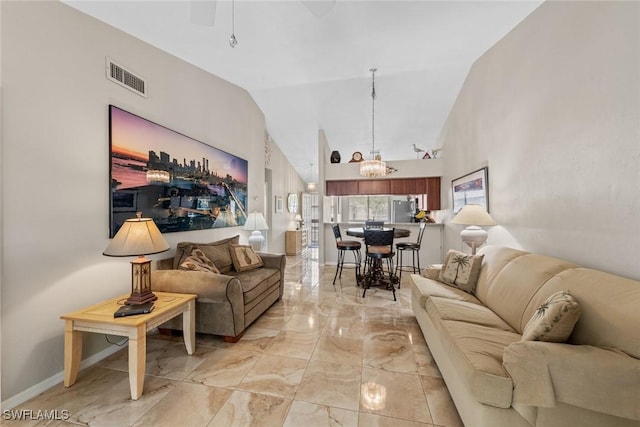 living room with a chandelier, high vaulted ceiling, visible vents, baseboards, and marble finish floor