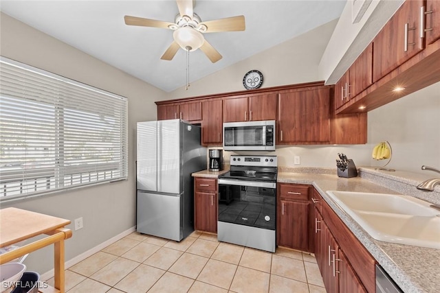 kitchen with vaulted ceiling, stainless steel appliances, a sink, and light countertops