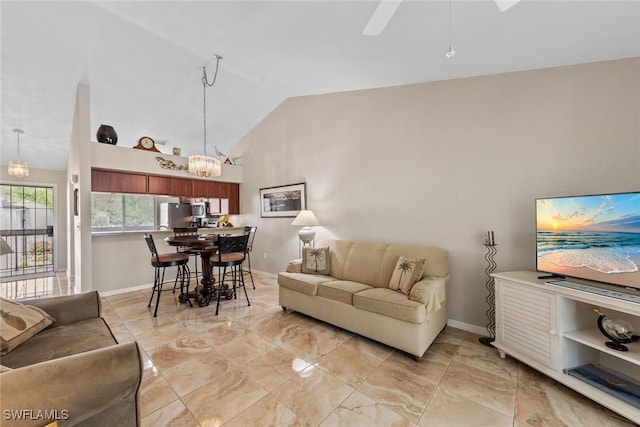 living area featuring lofted ceiling, ceiling fan with notable chandelier, and baseboards