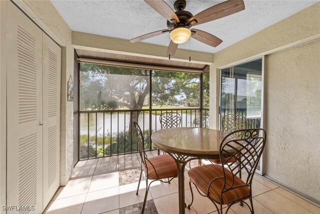 sunroom featuring a water view and ceiling fan